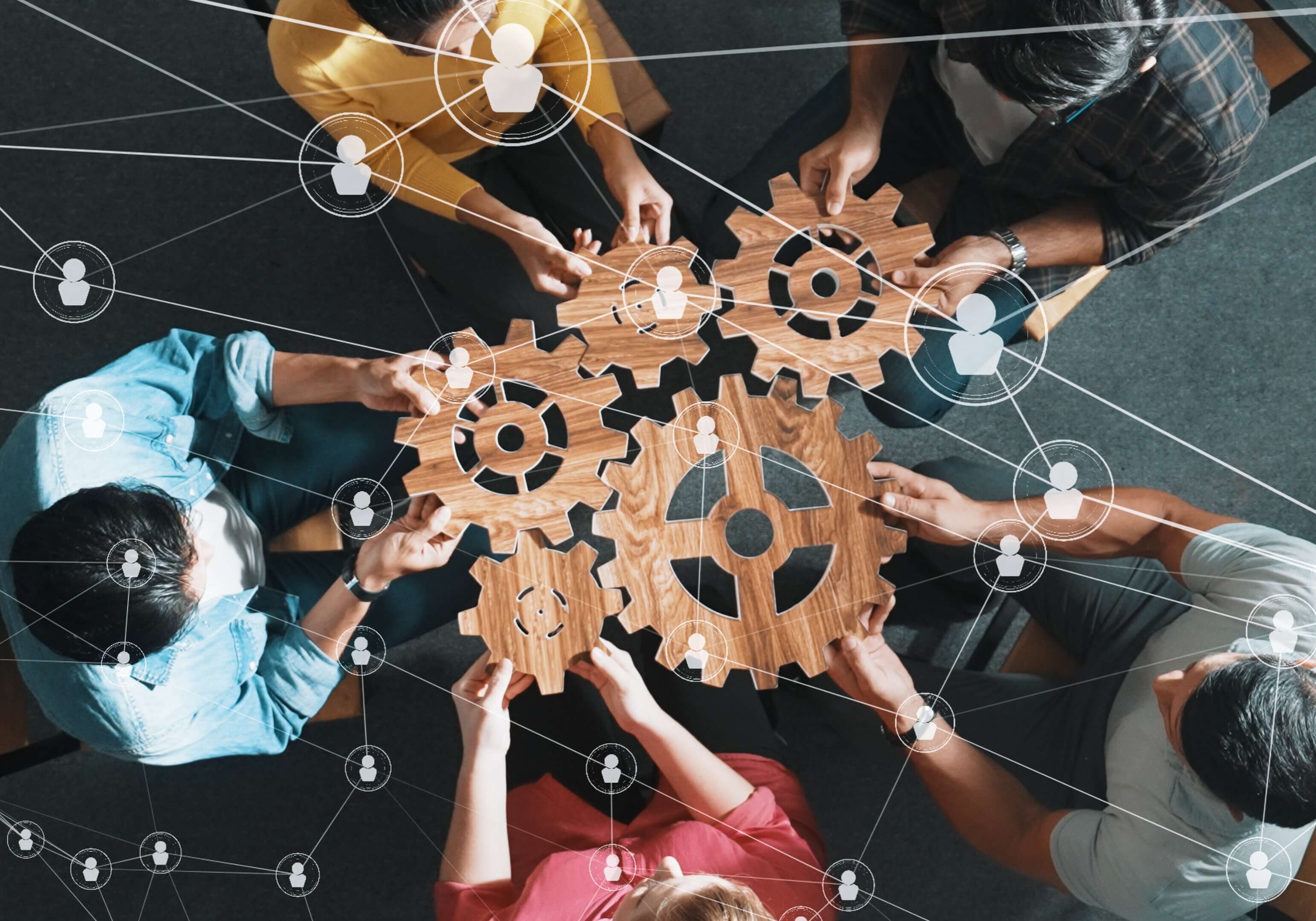 People connecting wooden gears, representing teamwork.